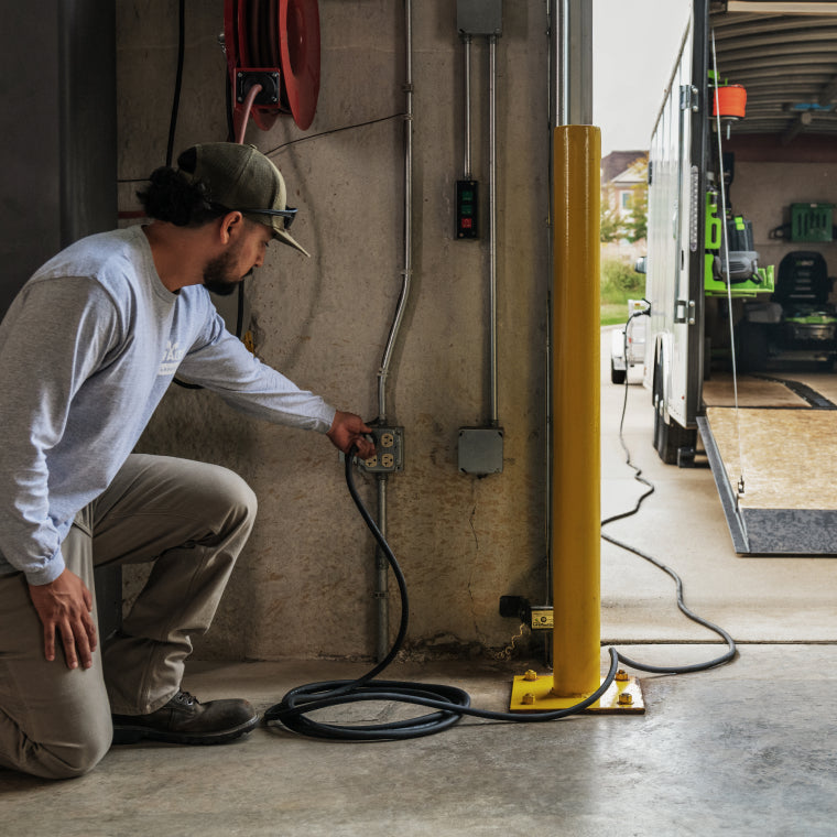 Man plugging PGX™ Commercial Charging system into a standard 15A outlet in a garage