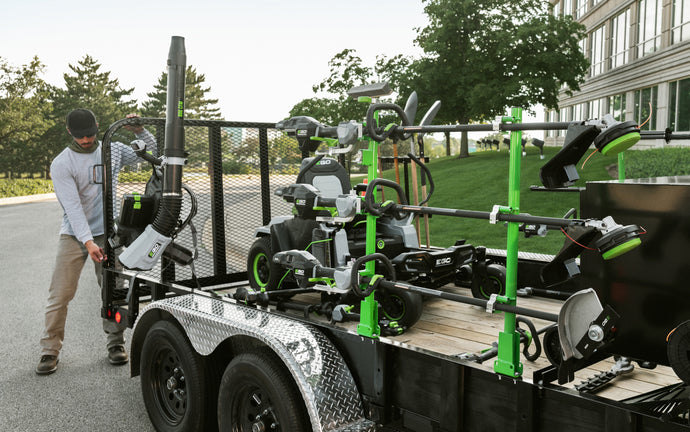 Man loading EGO Commercial equipment onto a landscaping trailer